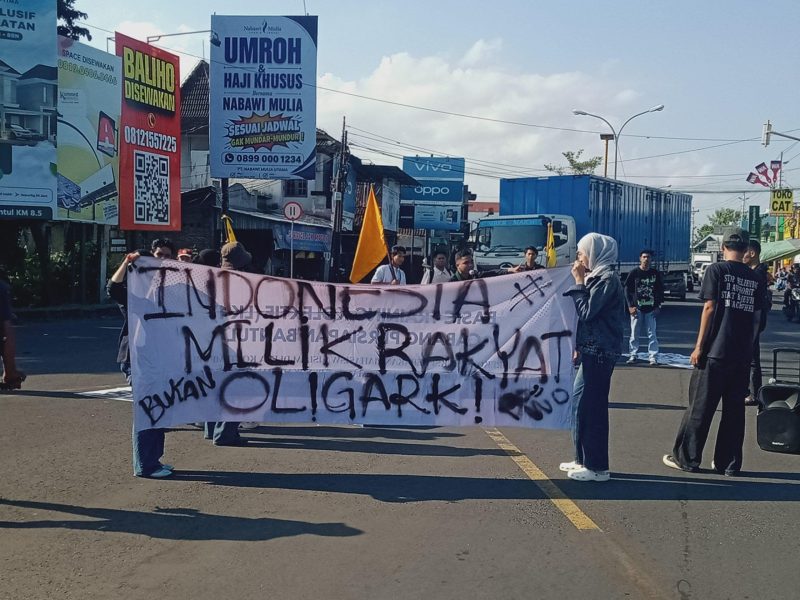Massa aksi membentang spanduk bertuliskan